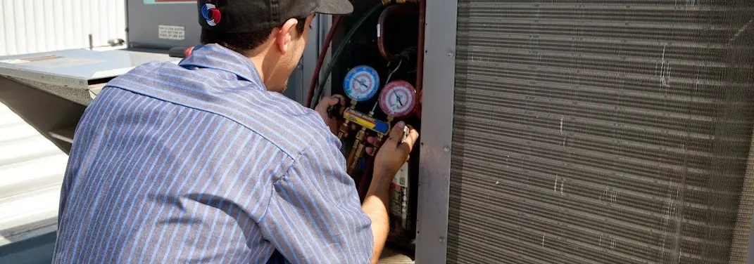 HVAC technician servicing a condenser unit in Royal Oak